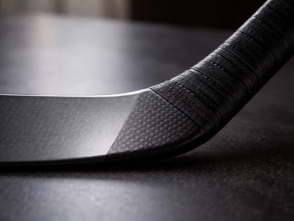Gros plan de deux crosses de hockey montrant jonctions et rigidité des matériaux, rendu réaliste et minimal