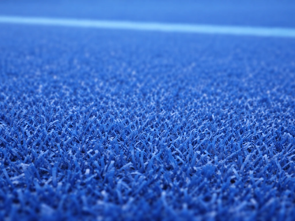 Gros plan sur un gazon synthétique bleu de hockey sur gazon, montrant la coloration des fibres et le marquage.